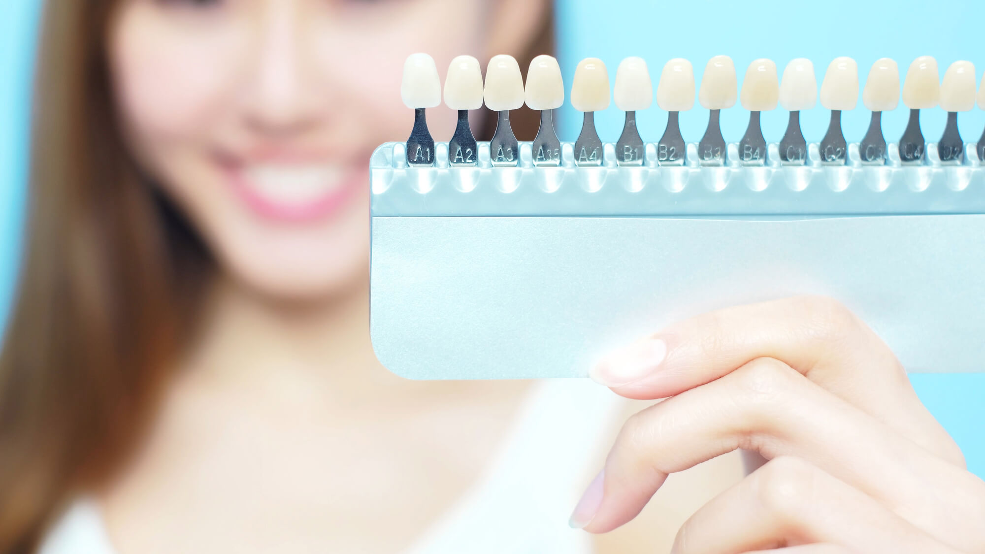 A girl showing a tooth color palette frequently used in procedures related to cosmetic dentistry in Lake Worth, Fl 