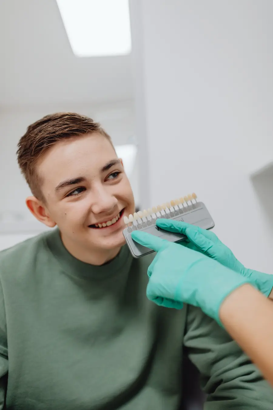 teeth-whitening-lake-worth-dentist-checking-tooth-shade-guide-on-smiling-teen